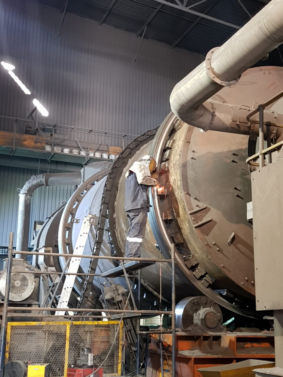 A welder working on a large rotary drum for a large and complex operation.